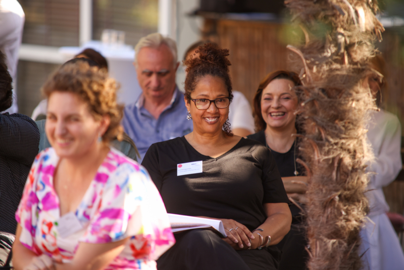 A photo of participants seating in a garden at the Exploring "BORDERS": A preview of the NECE Festival 2024 in Tirana with a focus on a smiling lady
