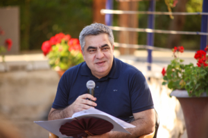 A male speaker at the A photo of participants sitting in a garden at the Exploring "BORDERS": A preview of the NECE Festival 2024 in Tirana