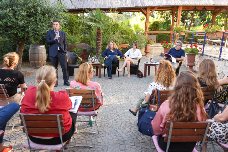Male speaker holding a microphone in front of seated participants at Exploring "BORDERS": A preview of the NECE Festival 2024 in Tirana