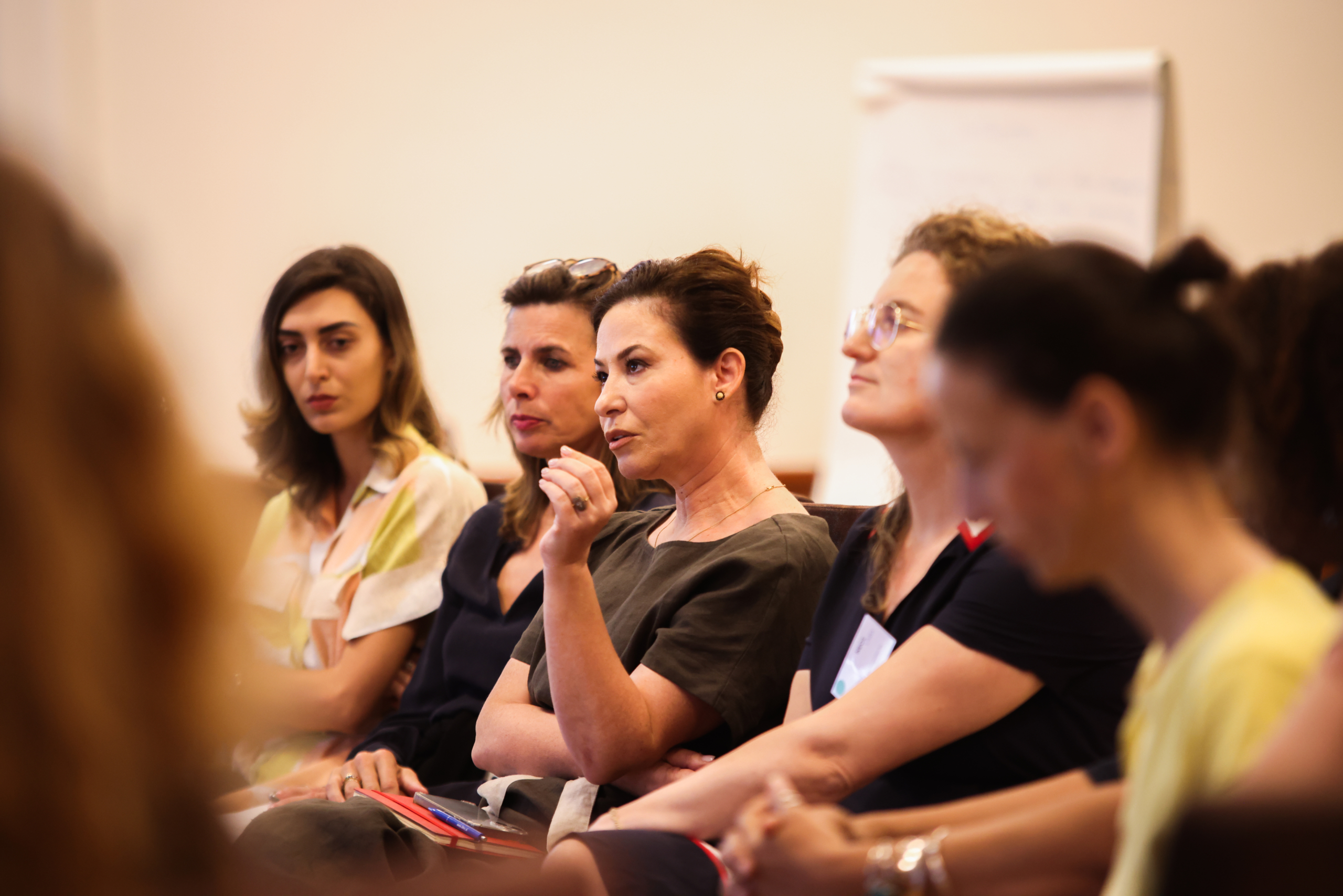 An indoor photo of participants seating in a garden at the Exploring "BORDERS": A preview of the NECE Festival 2024 in Tirana with a focus on a talking lady