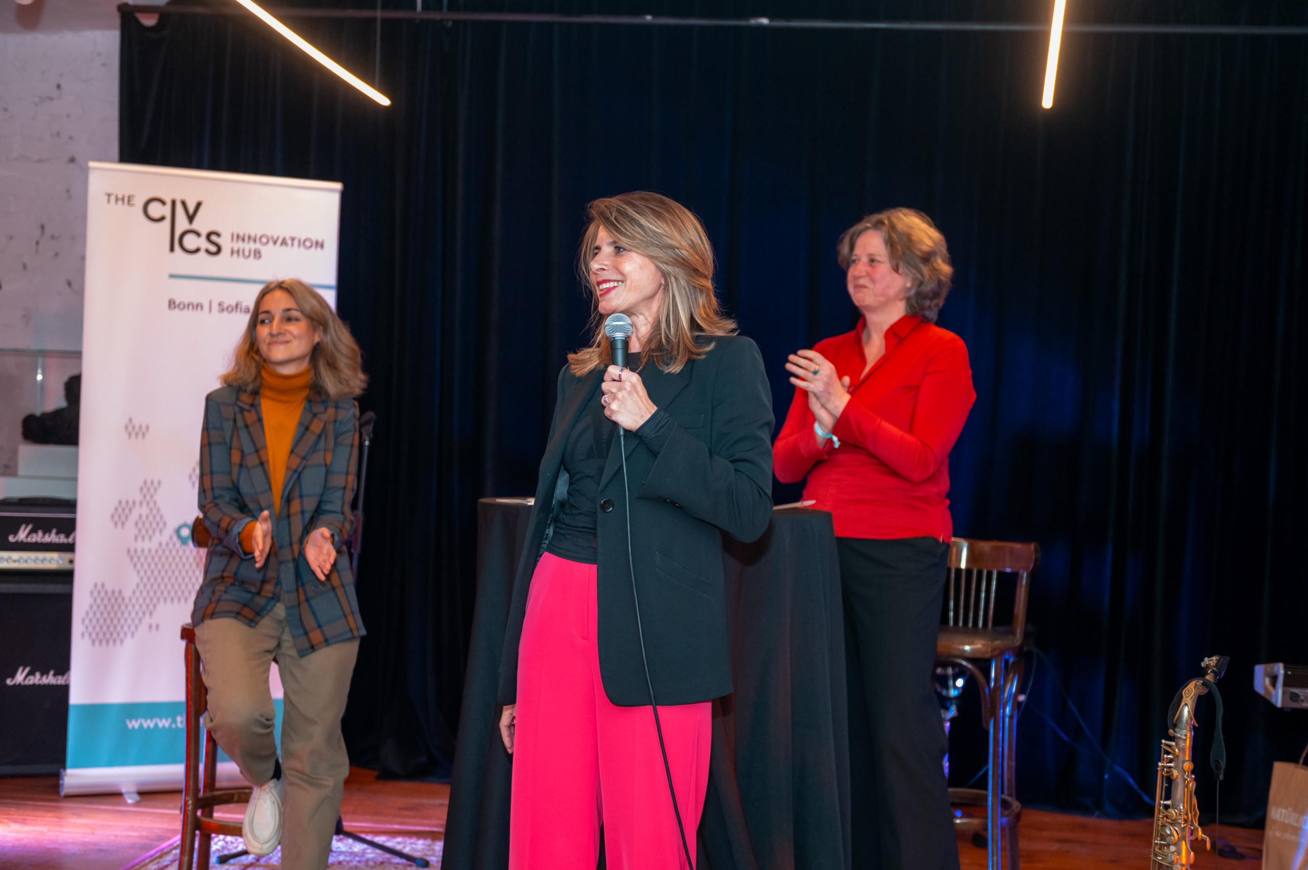 © THE CIVICS Innovation Hub | Geri Lula Louisa Slavkova, Anja Ostermann and Caroline Hornstein Tomić on stage during NECE Festival 2024. A "Civics Innovation Hub" banner is visible.