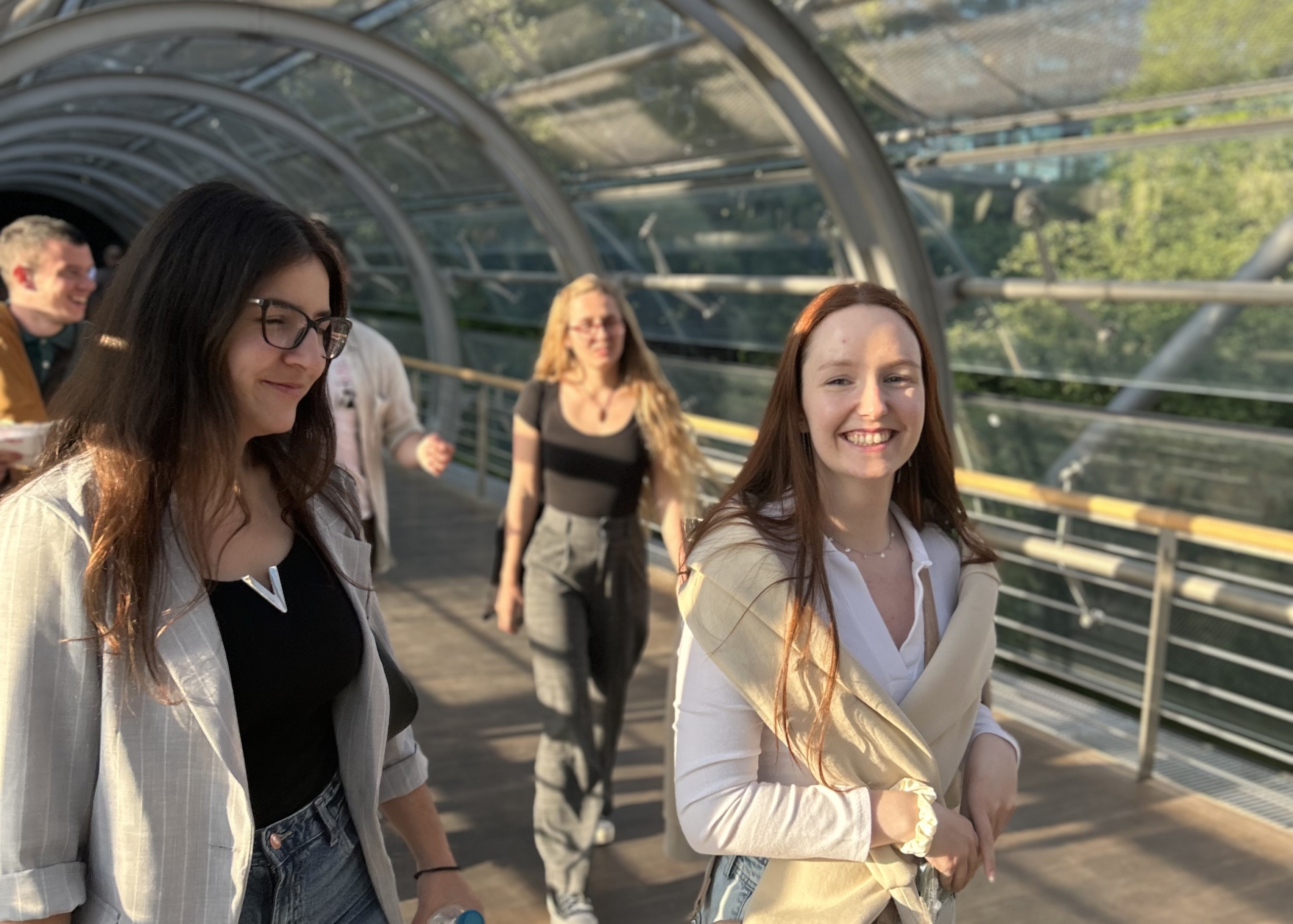 © THE CIVICS Innovation Hub Participants in the NECE Lab walking through a glass tunnel and smiling.