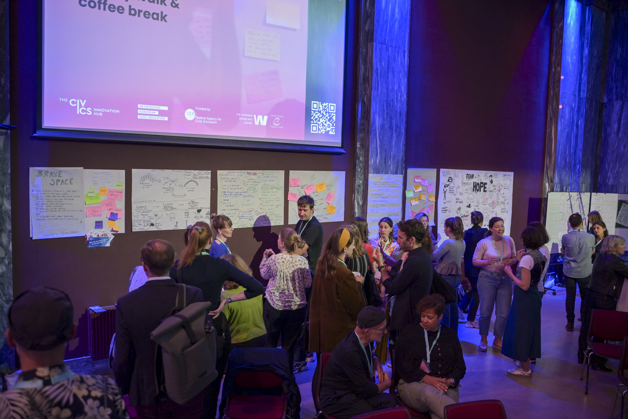 © THE CIVICS Innovation Hub / Werner Anderson Participants engage in discussions during the NECE Festival: HOPE, surrounded by posters with notes.