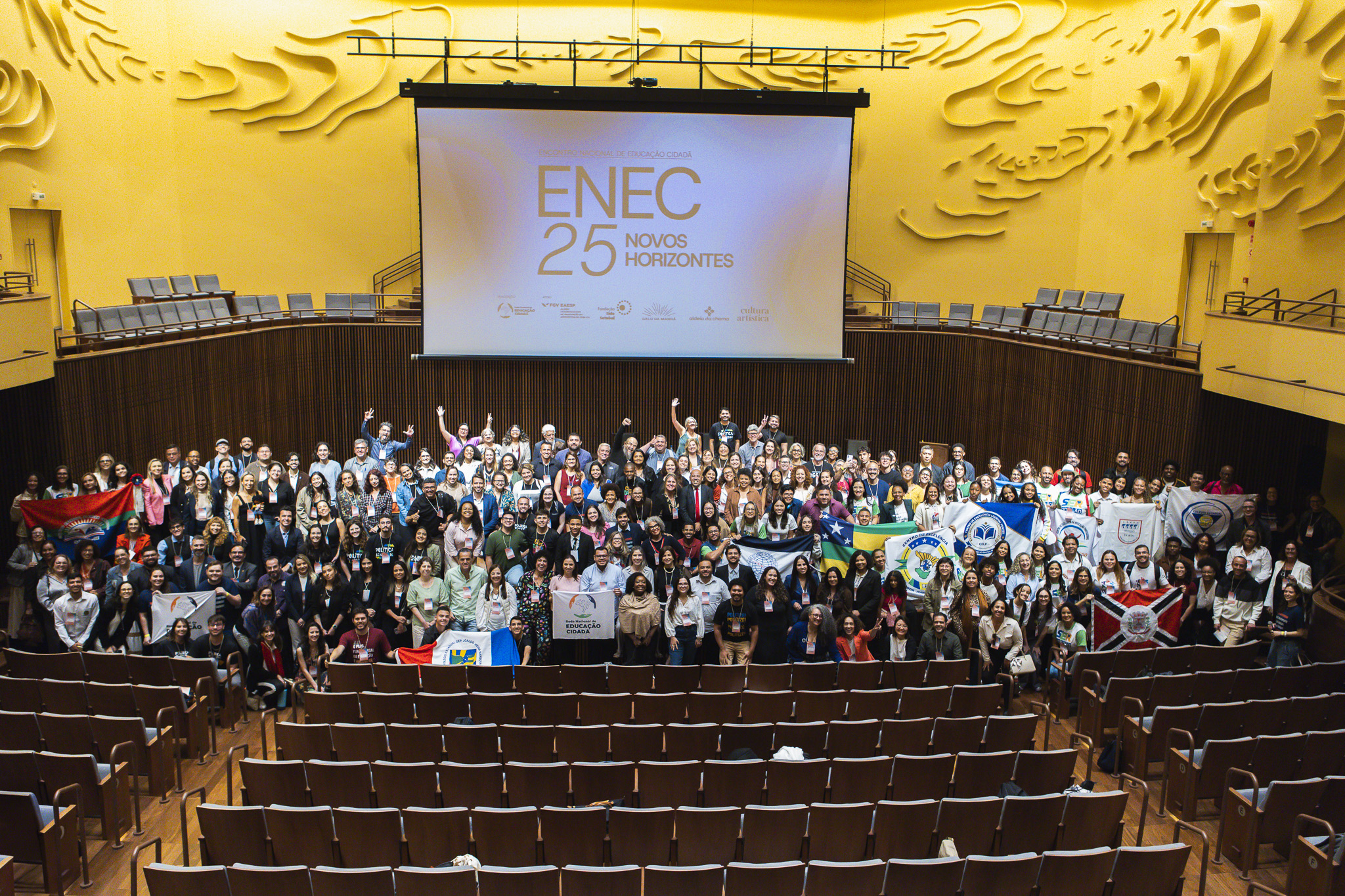 © RedeNEC The photo shows a big auditorium, where all guests are gathered on stage to take a group picture.